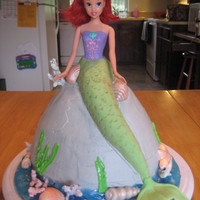 Arial Arial. The cake is frosted with buttercream, and the tail (fin) and shells are done in fondant, and the coral is made out of royal icing.