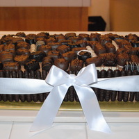 Chocolate Heaven Chocolate cake with dark chocolate ganache icing. It's bordered with dark chocolate graham cracker fingers and a silk ribbon; and...