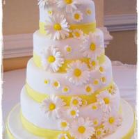 Fondant Covered Daisy Wedding Cake Fondant covered yellow cake with buttercream icing. The daisies were made out of gum paste and the ribbon is fondant.