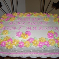 Drop Flower Cake pink and yellow drop flowers, green leaves, shell border with pink ruffle and white dots as accent to the sides