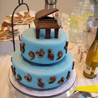 Chas' Piano Concert Cake Light blue fondant tiered cake with chocoalte grand piano on top and music symbols on cake sides.
