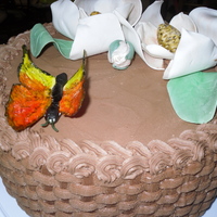 Magnolia Flower And Butterlfy classic buttercream cake with chocolate buttercream icing done in basket weave pattern. Flowers, leaves, and butterfly made from gum-paste...