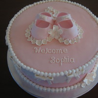 Pretty In Pink Baby shower cake with booties and gumpaste flowers in heart shape.