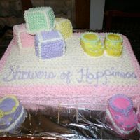 Baby Shower Cake Blocks are made of cake and frosting decor and booties are made of cupcakes and frosting decor.