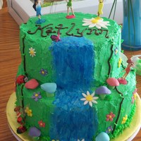 Tinkerbell And Friends Fairy Cake 2 tier round cake. Mushrooms and flowers are made of fondant. Fairies and bugs are toys. Everything else is buttercream. Waterfall was made...