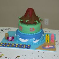 Hula Graduation Cake Vanilla cake, buttercream filling, and fondant topping. The volcano is rkt covered in fondant. The beach is brown sugar.