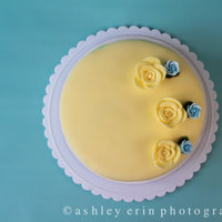 Yellow Rose Cake cake covered in yellow fondant. decorated with yellow fondant roses and blue roses.