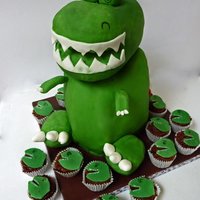 Lexzie's T-Rex Cake Chocolate Cake covered with fondant and matching mini-cupcakes. Dino head, tail and feet are made out of rice crispies.