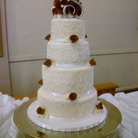 4-Tier Wedding Cake Cake is Red Velvet with cream cheese filling. Tiers are covered in MMF with royal icing scroll work. Roses are made out of gumpaste.