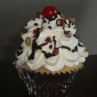 Banana Split Cupcakes White cupcake with banana cream cool whip icing, chocolate drizzle, pecans and a cherry on top!