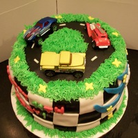 Race Track Cake yellow and chocolate checkerboard cake with black chocolate mmf and vanilla colored mmf, vanilla bc grass and matchbox car toppers. tfl
