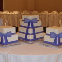 Purple Bows Center cake is 4 tier stacked cake, 14", 12", 10", 8". Two smaller cakes are 10" and 8" dummy cakes. Fondant/...