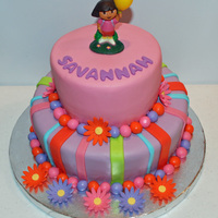 Dora The Explorer Cake Chocolate cake filled with chocolate buttercream. Flowers are fondant and Dora is actually a candle. Thanks for looking! :)
