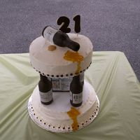 Welcome To 21 A tiered cake held together by chocolate fondant bottles with edible mock labels. On top there is a "spilled" chocolate fondant...