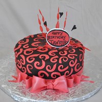 Red Swirls Covered in chocolate fondant with hand cut fondant swirls and gum paste bow and plaque.