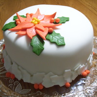 Poinsettia Cake Fondant covered cake. I used a leaf shaped cookie cutter for the poinsettia leaves. I used a holly leaf cookie cutter for the border.