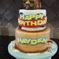 Woody Themed Toy Story Birthday Cake 8" and 6" WASC cake with Strawberry Mousee filling. (from recipe on CC) Coved in MM Fondant. Fence was made with Gumpaste and the...