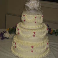 Simple Hearts 3 Tier Wedding Cake Three tier cake with white butter cream frosting, garland piping and rose colored piped hearts. Simple but sweet!