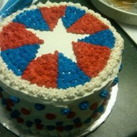 4Th Of July Star Covered cake with white buttercream and filled in wedges with red/blue star tip, leaving white star shape in center.