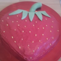Strawberry Cake Heart shaped cake with red marshmellow fondant, and green trim and yellow seeds.