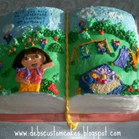 Dora Storybook Cake Hand carved open book cake, decorated primarily in buttercream with a few fondant accents.
