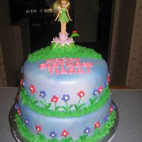 Tinkerbell Cake Two tier yellow cake with buttercream filling covered in fondant. Buttercream flowers and grass.