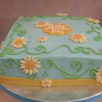 Daisy Mother's Day 10 inch square carrot cake with cream cheese frosting. Gumpaste band on bottom & plaque on top. Modeling chocolate daisies. Buttercream...