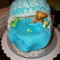 Baby Shower Basinette basket weave base with gum paste ruffles on the top. Gum paste bear, rattle, airplane, car, pillows, and blanket.