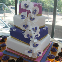 Purple, Fuschia, White Wedding Cake With Orchids Fondant cake with handmade gumpaste orchids.