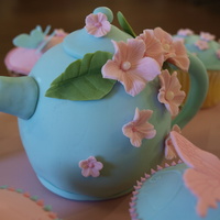 Teapot Cake And Cupcakes Mini Teapot cake with matching cupcakes. Vanilla cake covered in White chocolote and fondant. All flowers, leaves and butterflies are made...