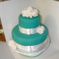 First Tiered Cake MMF and fondant roses. Ribbon border is hiding lots of mistakes! Now just pray it make the 5 hour trip to Grannie's for her birthday...