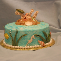 Seaside Buttercream light blue with sponge paint in darker blue. 8 inch round cake. Tylose paste decorations. Brown sugar for sand.