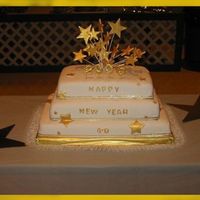 Welcome 2005 Happy New Year cake covered in white fondant. Stars on top made in run sugar and then painted with Gold luster dust. Stars attached to the...