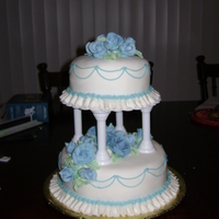 Blue Tiered Cake The cake is strawberry and yellow covered in white fondant with a ruffle, blue string work and fondant roses and leaves. This is my final...