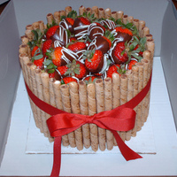 Dipped Strawberry Cake French vanilla cake iced in chocolate buttercream, covered in chocolate pirouettes, and topped with fresh chocolate covered strawberries.