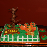 Pumpkin Patch Birthday 18 inch square WASC cake, iced in buttercream. Fondant fence, and "wood" name sign. White chocolate mold pumpkins. Hay bale is...