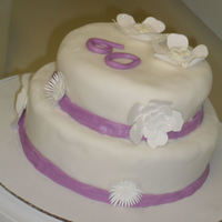 Judy's 60Th Bday Cake Coconut Creme cake with vanilla buttercream frosting covered in white fondant with purple fondant accents and white flower accents.