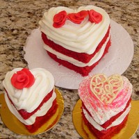 Mini And Individual Red Velvet Heart Cakes a 5" red velvet heart cake and 2 cupcake sized red velvet hearts. Sides are exposed for color and top designs vary.