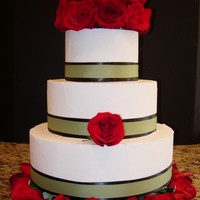 Modern Wedding buttercream icing, layered ribbons (black and green) and red flowers.
