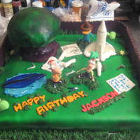 Phineas And Ferb 16 x 16 chocolate cake with chocolate buttercream. MMF airbrushed. Fence and all accessories are fondant. Tree is RKT covered with MMF....