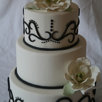 Black N White Magnolia Cake white fondant, black 3 d scrolls, finished off with magnolia flowers and simple leaves for a touch of color.