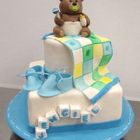 Baby Bear Fondant Baby bear sitting on painted quilt, gumpaste booties, and blocks spelling the baby's name.