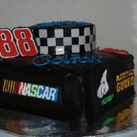 Nascar Cake Chocolate Cake covered in Chocolate Butter Cream accented with royal icing decals.