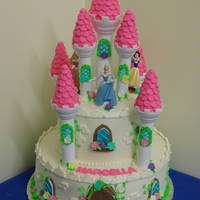 Disney Princess Castle 2 tier, fondant cake sprayed with edible shimmer dust and fondant detailing such as trim on windows and door and royal icing dainty flowers...