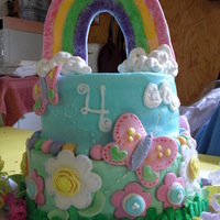 Rainbow And Butterflies Buttercream icing with fondant and buttercream work on cake.Rainbow on the top is made from almond bark, sprinkled with colored sugar.