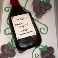 Wine Bottle Birthday Cake This cake was created for a wine themed party. The bottle is covered with Fondant and the grapes are mini cupcakes with buttercream.