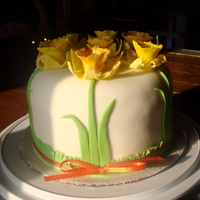 Spring Daffodil Cake White fondant covered daffodil cake with ribbon tied around the bottom.