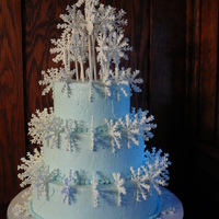Snowflakes 3 tiers stacked, covered in light blue buttercream, sprinkled with clear glitter, with royal icing snowflakes