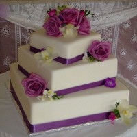 Jacake Top tier is real cake, bottom two are dummy cakes. Ribbon around edge and real flowers.