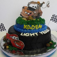 Tow Mater And Lightining Mcqueen Cake Chocolate fudge cake with buttercream frosting. Tow Mater and Lightening McQueen made out of gum paste and are drawn by hand and painted.